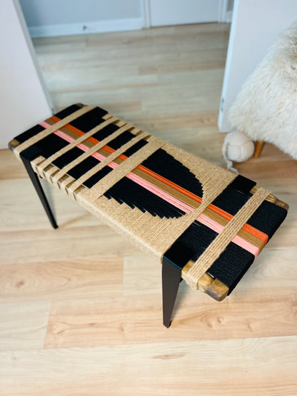 a bench with a woven seat and a wooden frame, placed on a wooden floor.