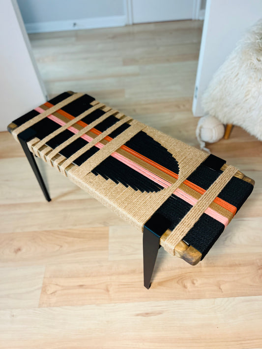 a bench with a woven seat and a wooden frame, placed on a wooden floor.