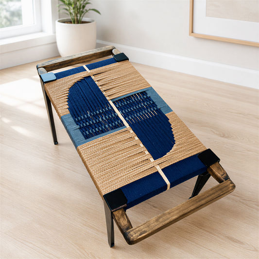 a wooden bench with a woven seat and backrest, placed on a wooden floor in a room with a window.