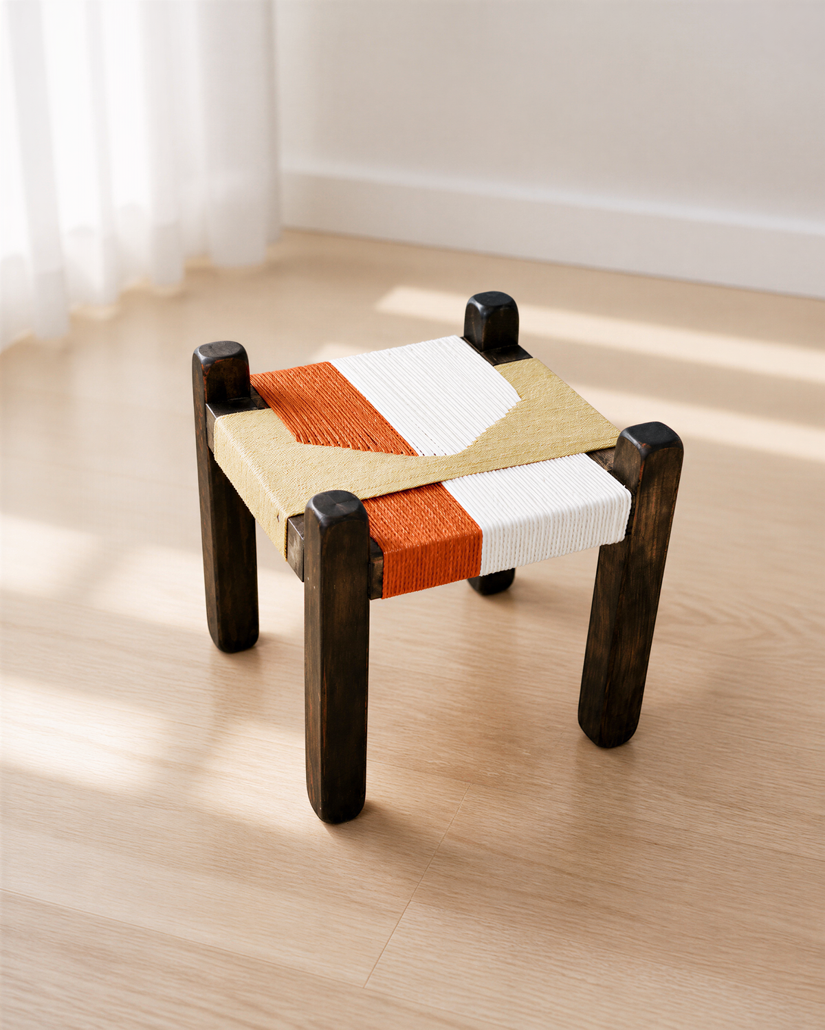 A modern, wooden stool with a woven seat and legs, placed on a wooden floor.