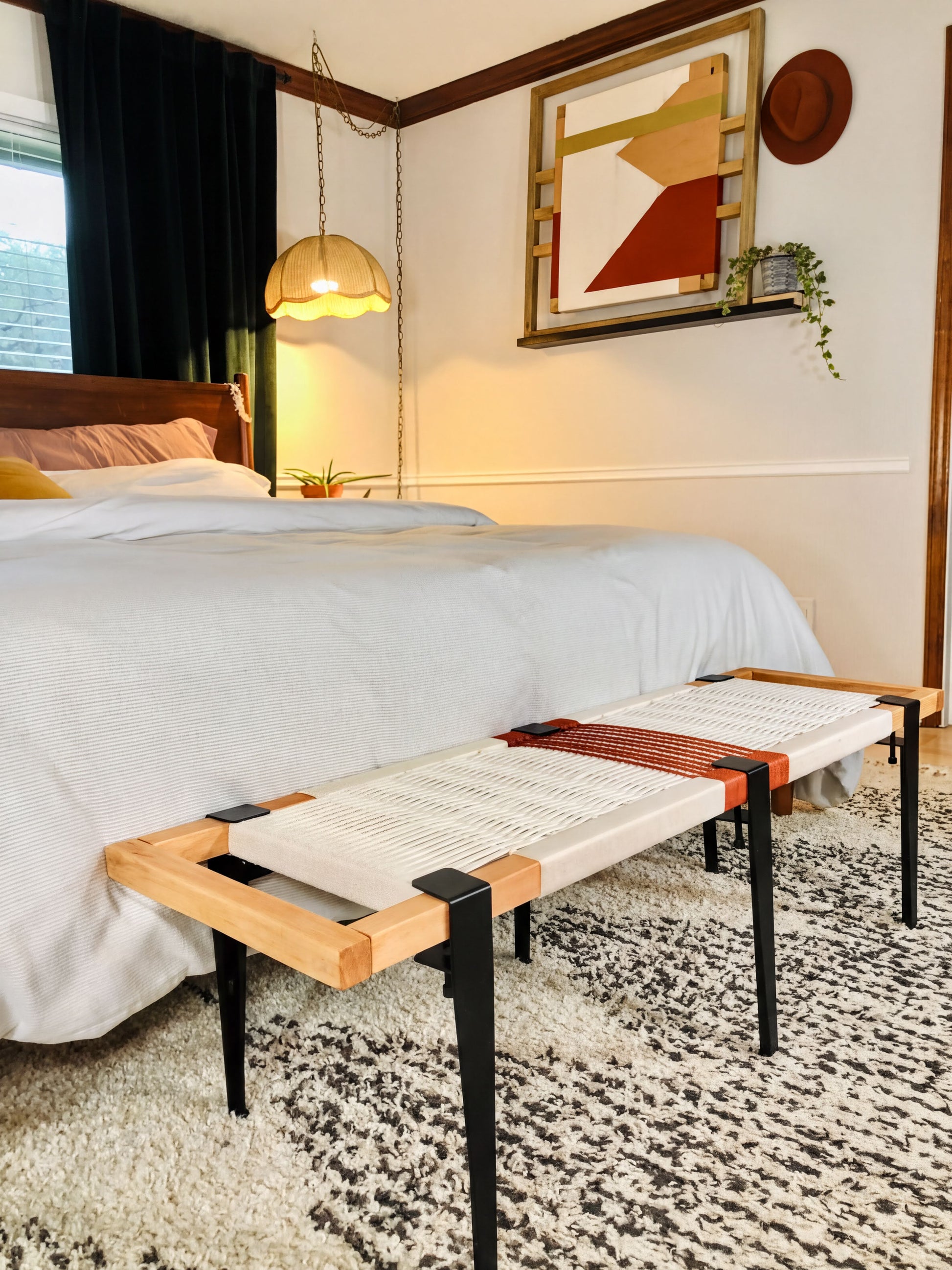 a bedroom with a bed, a wooden bench, and a colorful abstract painting on the wall.