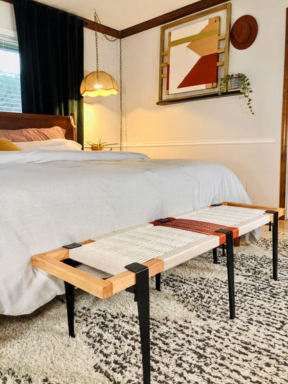 a bedroom with a bed, a wooden bench, and a colorful abstract painting on the wall.