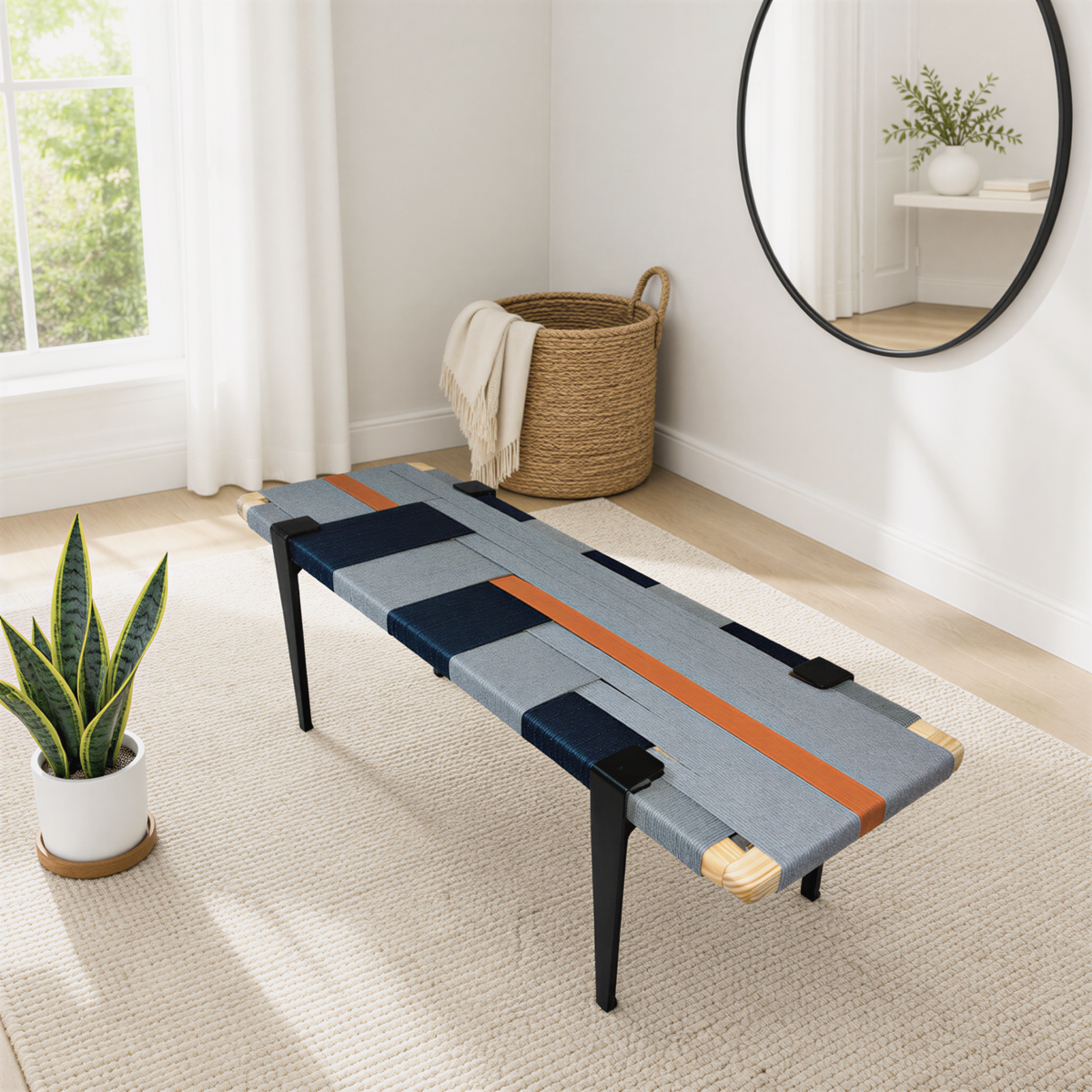 a modern living room with a unique bench-style table with a geometric pattern in shades of blue, orange, and gray. The table is placed on a beige rug, and there is a round mirror hanging on the wall above it. A woven basket is also present in the room, and a potted plant is visible on the left side of the image.