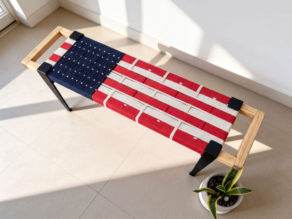 a bench with an American flag design, placed on a tiled floor next to a potted plant.