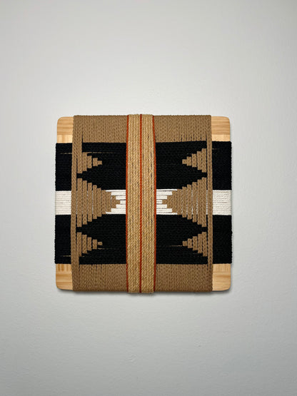a square-shaped woven textile with a geometric pattern in black, white, and brown colors.