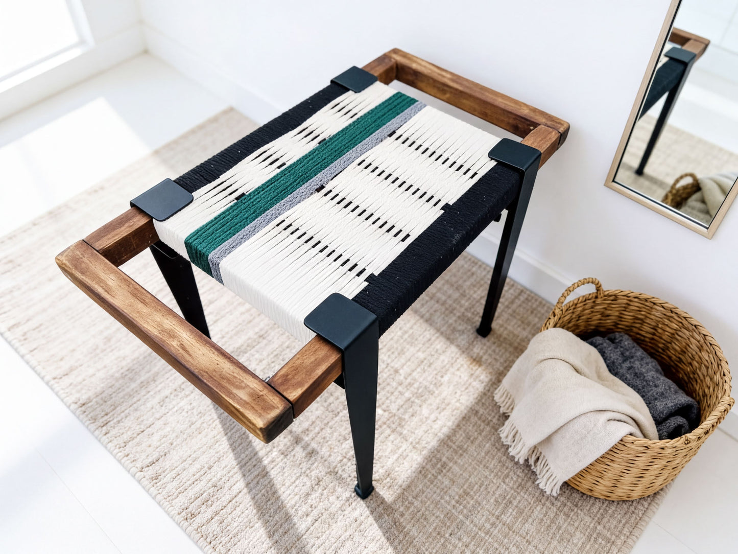 a wooden bench with a woven seat and a woven basket with a blanket and a scarf placed next to it.