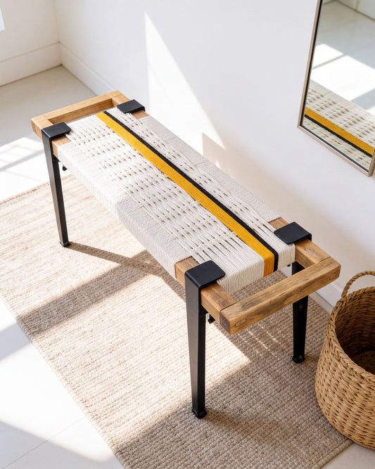 a modern bench with a woven seat and wooden frame, placed on a beige rug in a room with a mirror on the wall.