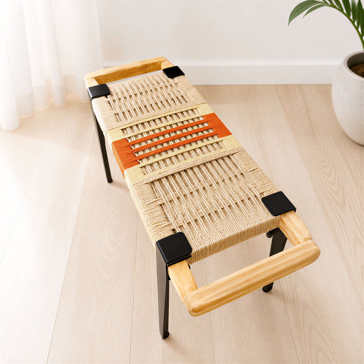 A woven bench with a wooden frame and black metal clamps, placed on a light-colored wooden floor.