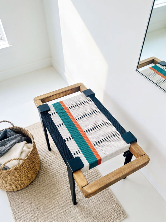 a modern, wooden bench with a colorful woven seat, placed on a beige rug in a room with a mirror and a basket.