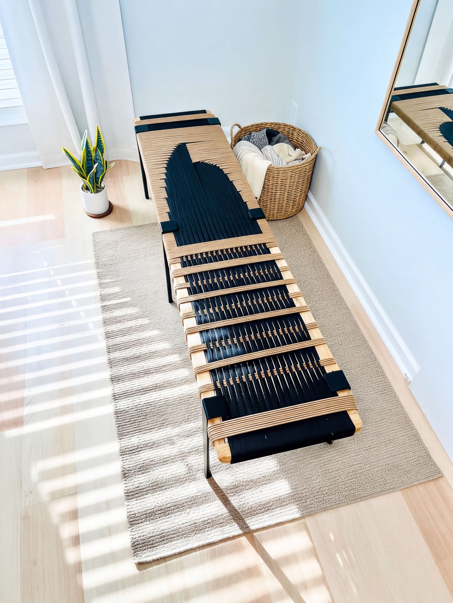 a modern black and brown bench with a woven seat, placed on a beige rug in a room with a window and a plant.