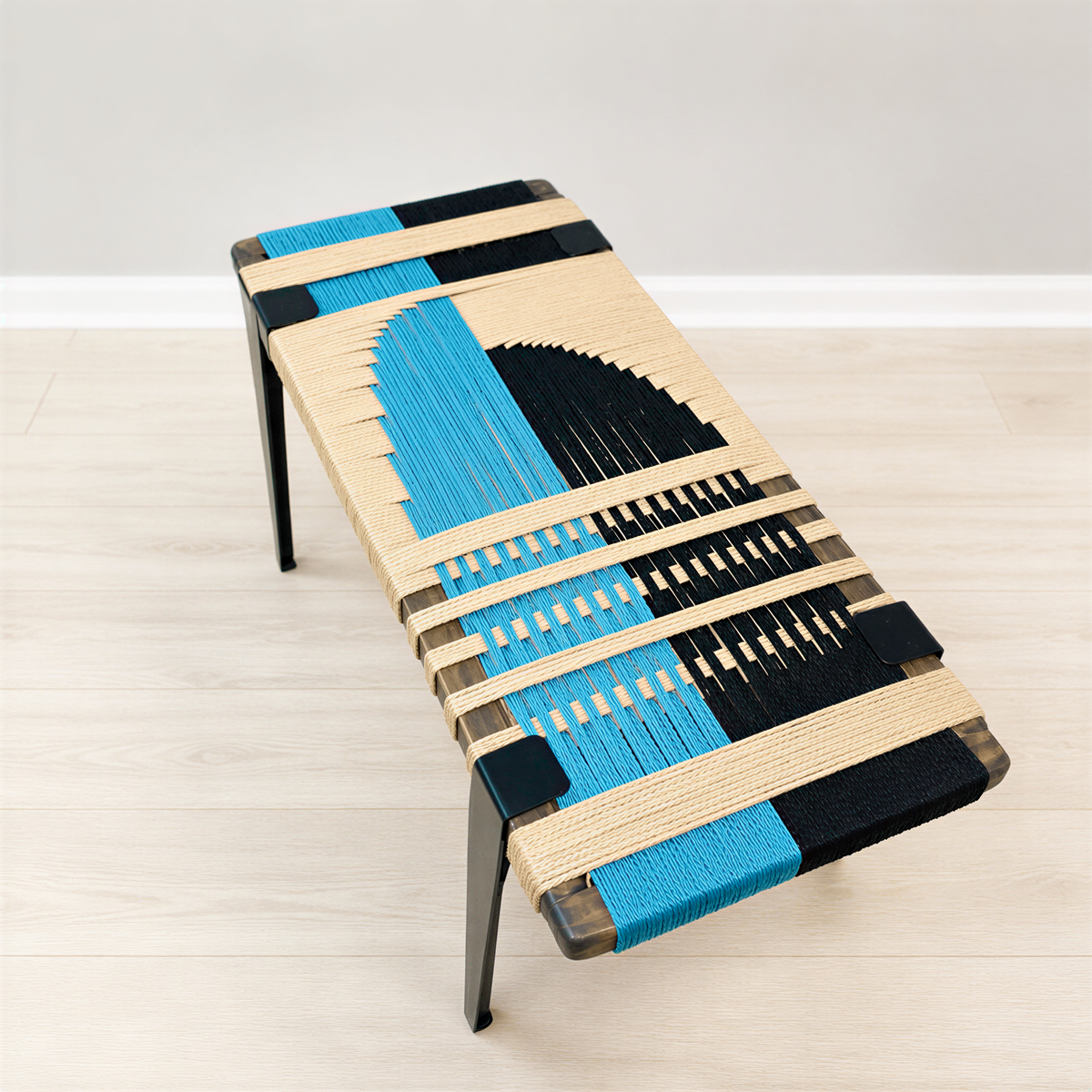 a modern bench with a unique design, featuring a combination of blue and black elements. The bench is placed on a wooden floor against a white wall, creating a visually appealing contrast.