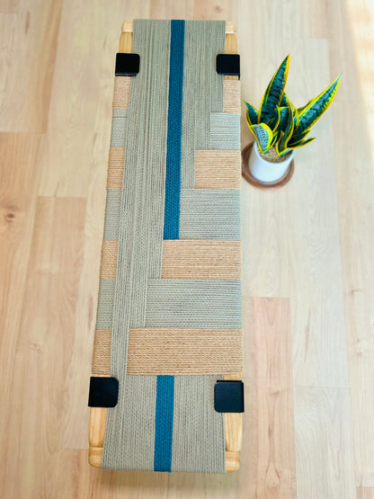 a wooden bench with a woven seat and a potted plant placed on a wooden floor.