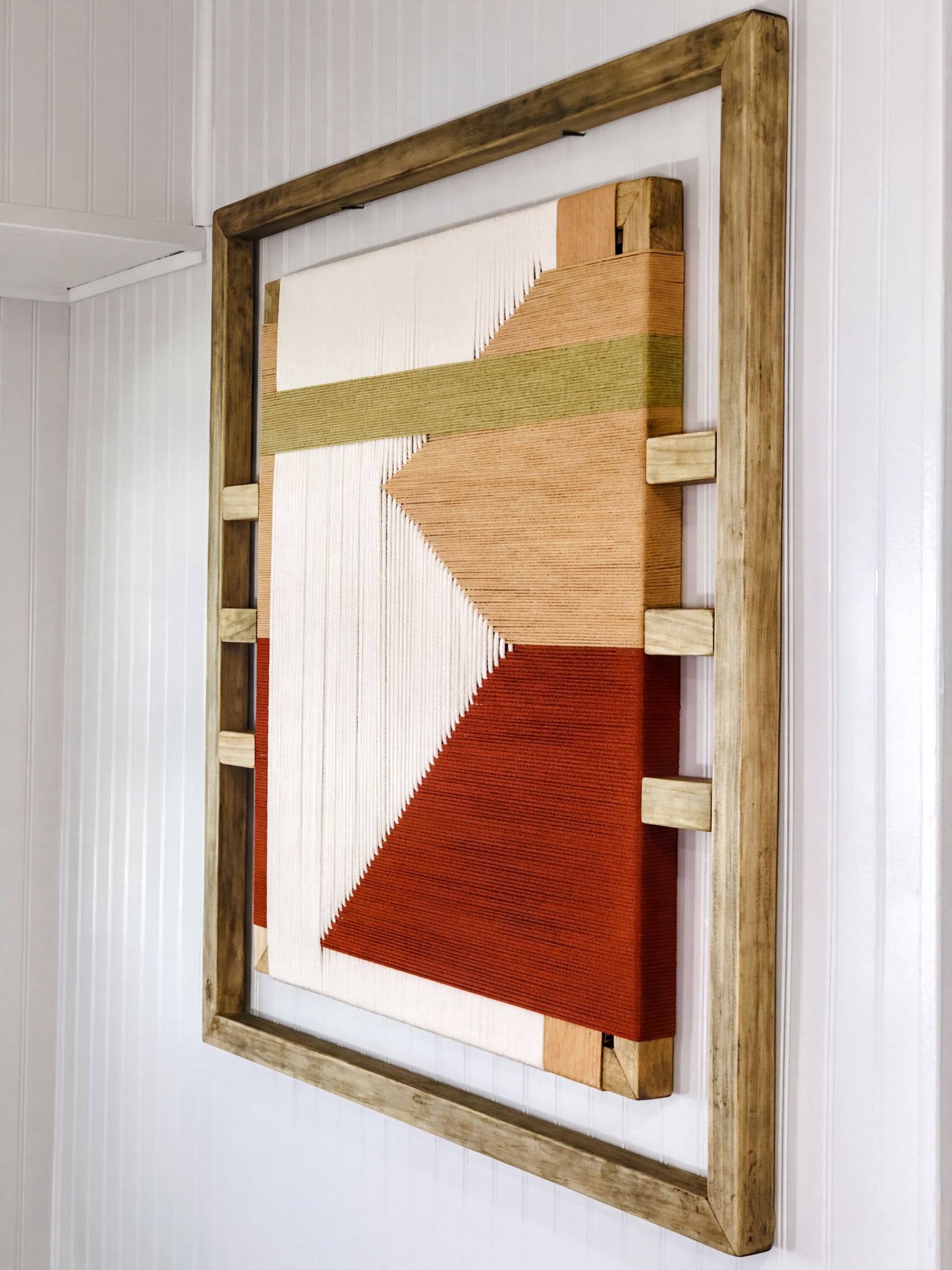 a wooden frame with a vibrant abstract artwork hanging on the wall.