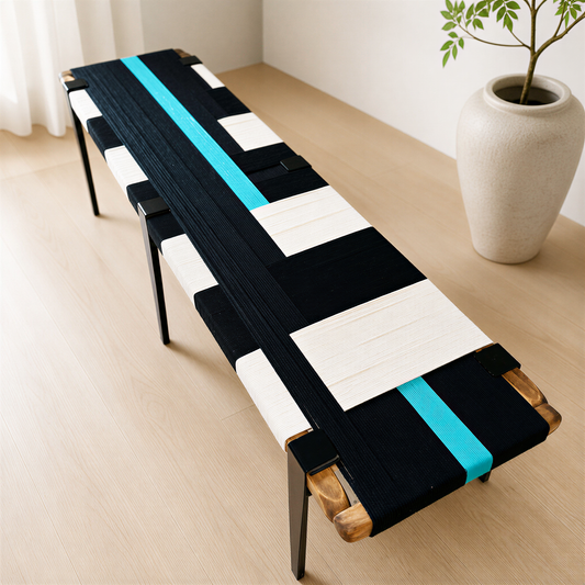a modern black and white bench with a striking blue stripe running along its length. The bench is placed on a wooden floor, and there is a white vase with a plant on the right side of the bench.