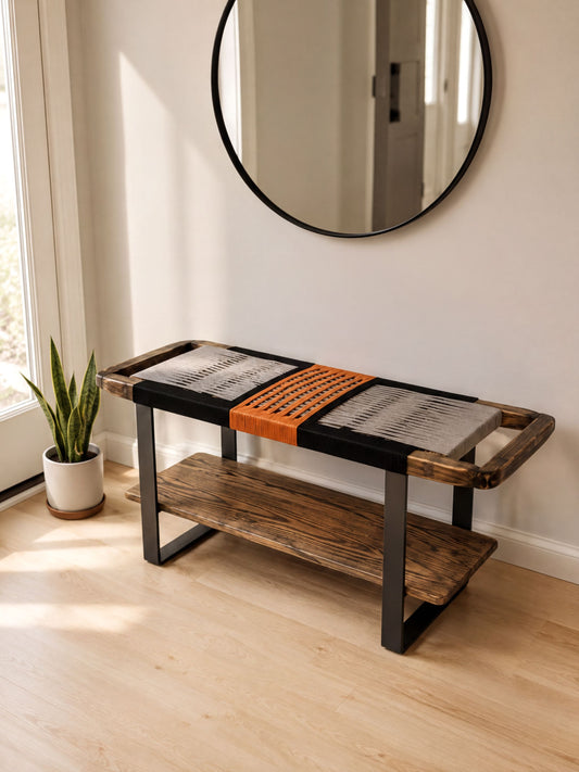 a modern, minimalist design with a wooden bench and a round mirror on the wall. The bench has a black and orange woven seat, and the mirror is mounted above it. The room has a clean, white color scheme with a wooden floor, and a potted plant is visible in the corner.