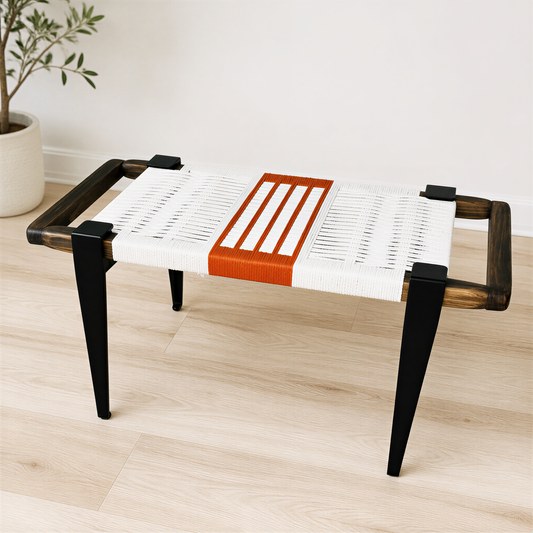 a modern bench with a woven seat and wooden legs, placed on a wooden floor against a white wall.
