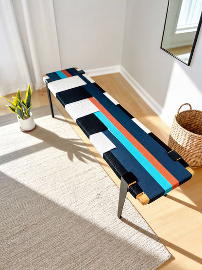 a modern, colorful bench with a black and white striped seat, placed on a gray rug in a room with a potted plant and a woven basket nearby.
