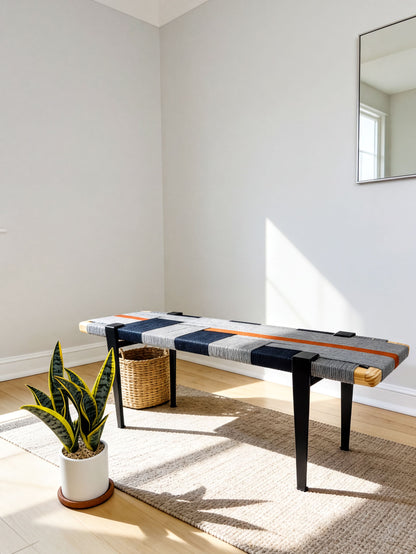 a modern bench with a striped seat and legs, placed on a beige rug in a room with a white wall and a plant in a white pot.