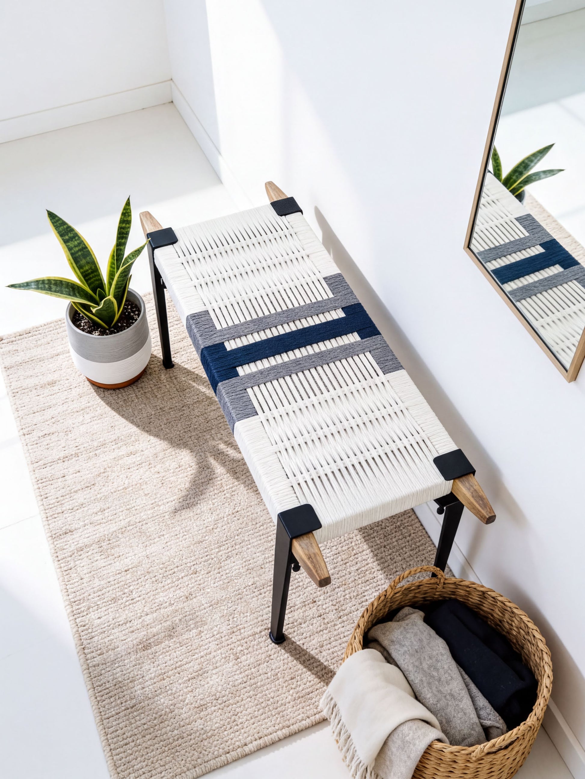 a modern, minimalist living space with a woven bench, a potted plant, and a woven basket.
