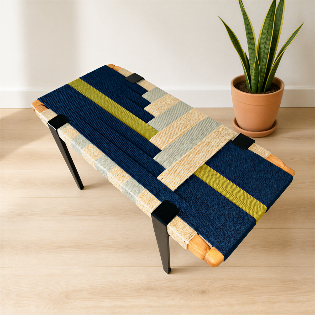 a modern, colorful bench with a woven seat and legs, placed on a wooden floor next to a potted plant.