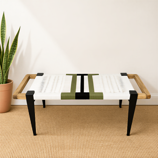 A modern, minimalist bench with a woven seat and wooden armrests, placed on a beige carpeted floor next to a potted plant.