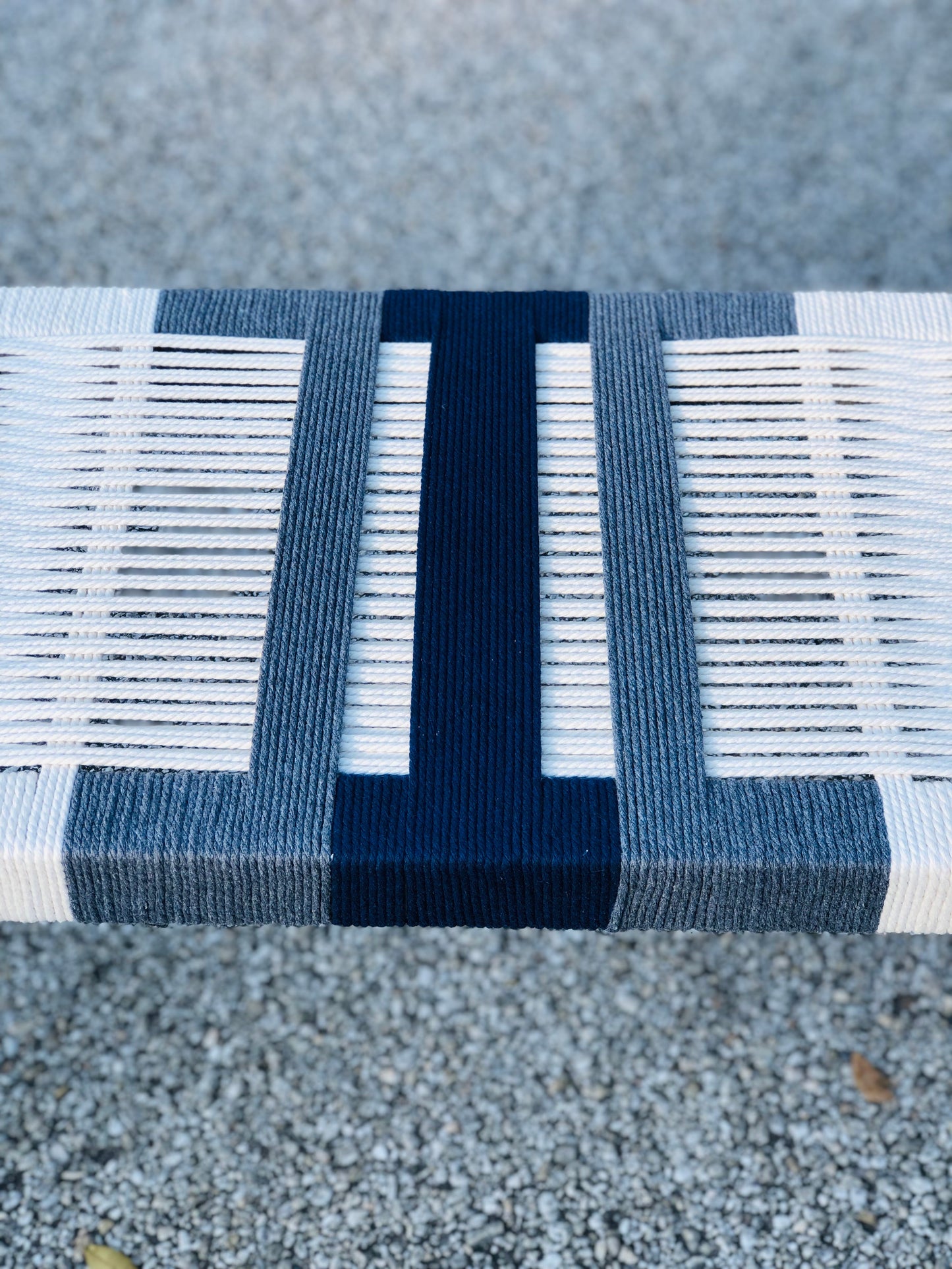 a close-up view of a bench with a blue and white striped design. The bench appears to be made of wood and has a textured surface.