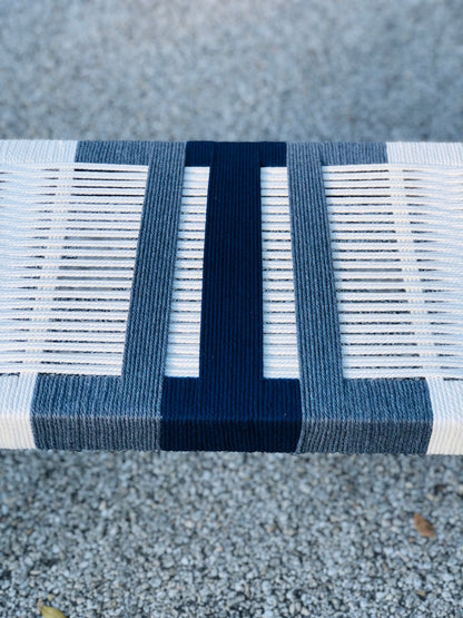 a close-up view of a bench with a blue and white striped design. The bench appears to be made of wood and has a textured surface.